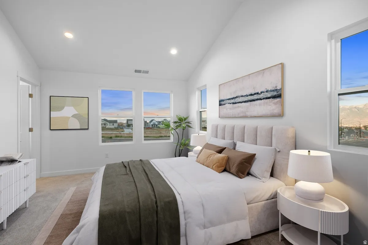 Spacious bedroom with vaulted ceilings, recessed lighting, multiple windows, and light-toned carpet flooring