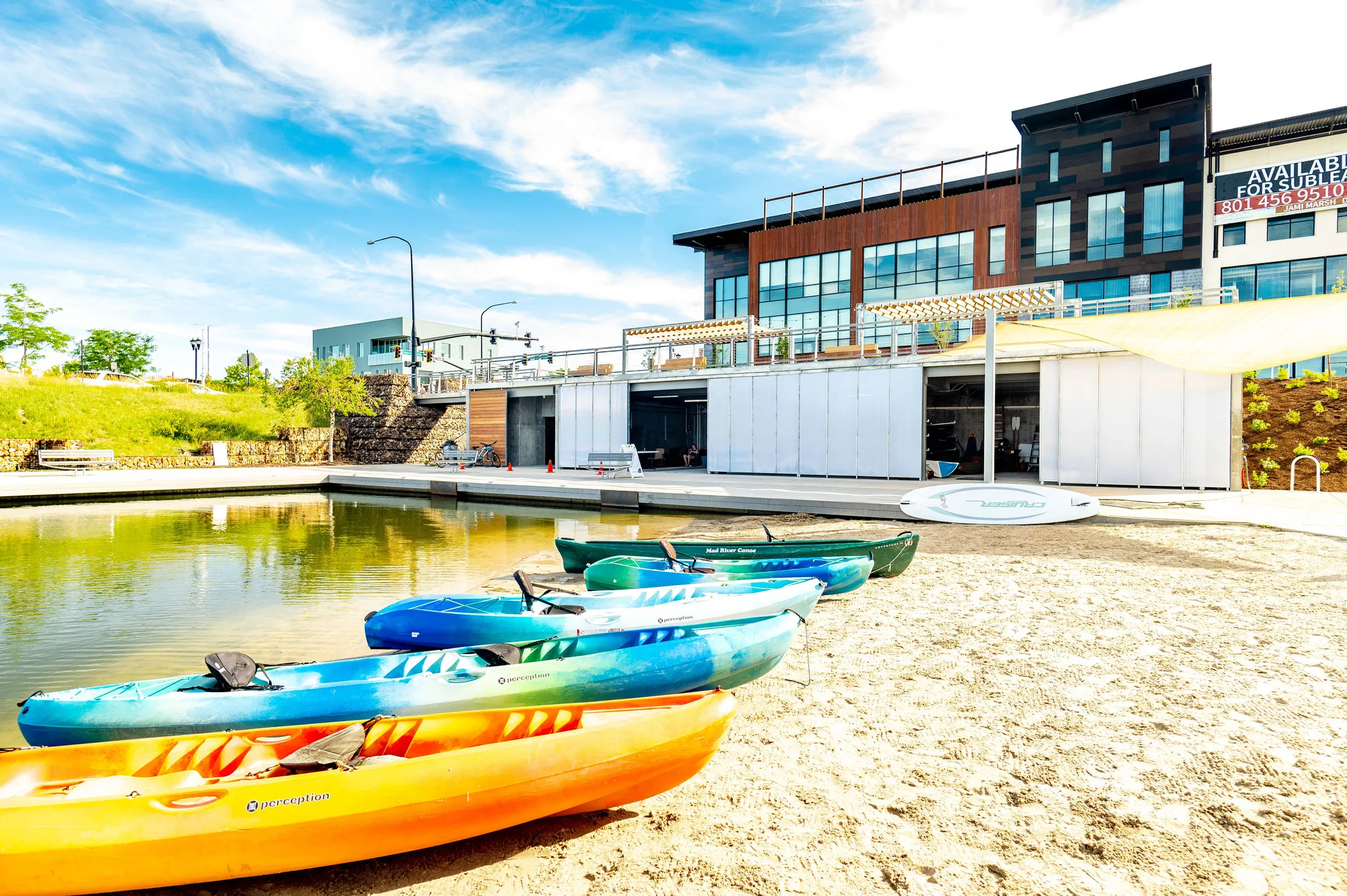 Waterfront property featuring a sandy shore, a modern building with large windows, and a dock