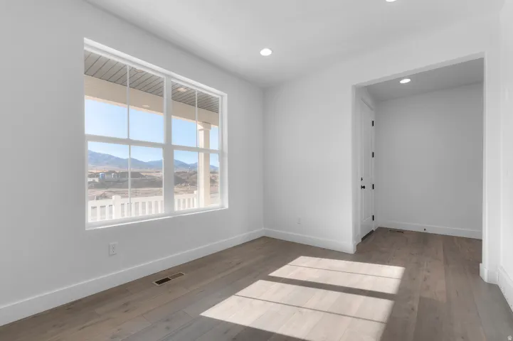 Spacious room featuring wood-finish flooring and recessed lighting