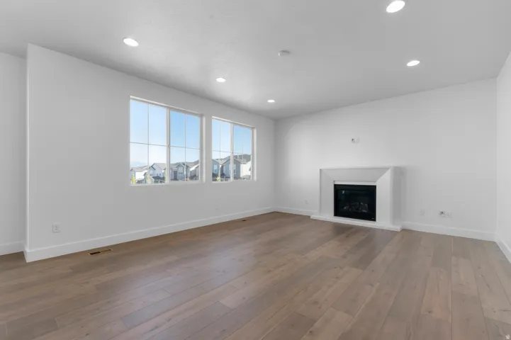 Spacious interior with wood-finish flooring, multiple windows, a built-in fireplace, and recessed lighting