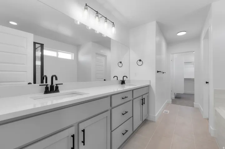 Dual sink vanity with light gray cabinetry, white countertops, and matte black fixtures