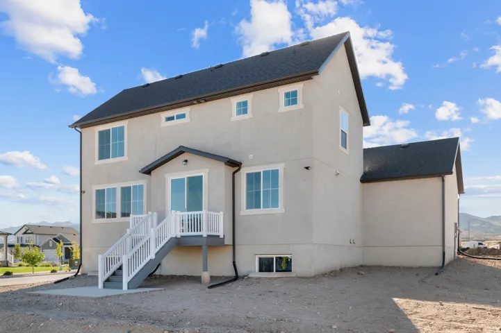 Stucco exterior with multiple windows, dark shingle roofing, and a patio with white railings