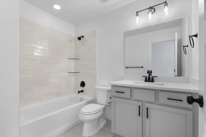 Bathtub with subway tile surround and integrated glass shelving