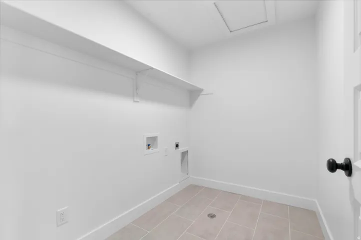 Utility room featuring a built-in shelf, plumbing hookups, electrical outlets, and tiled flooring
