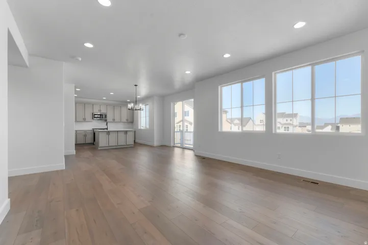 Open-concept living area featuring wood-finish flooring, recessed lighting, and large multi-pane windows