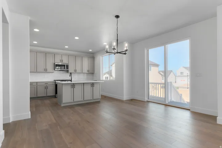Open-concept kitchen and dining area featuring wood-finish flooring, recessed lighting, and a modern chandelier