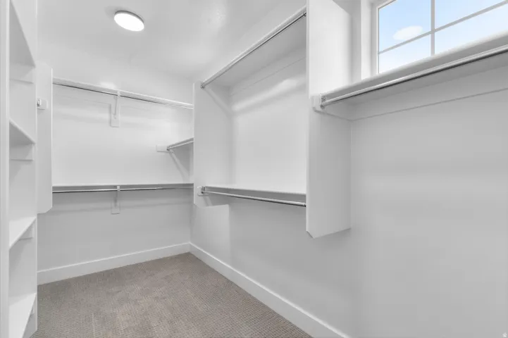 Built-in shelving, hanging rods, recessed lighting, window, and gray carpet flooring