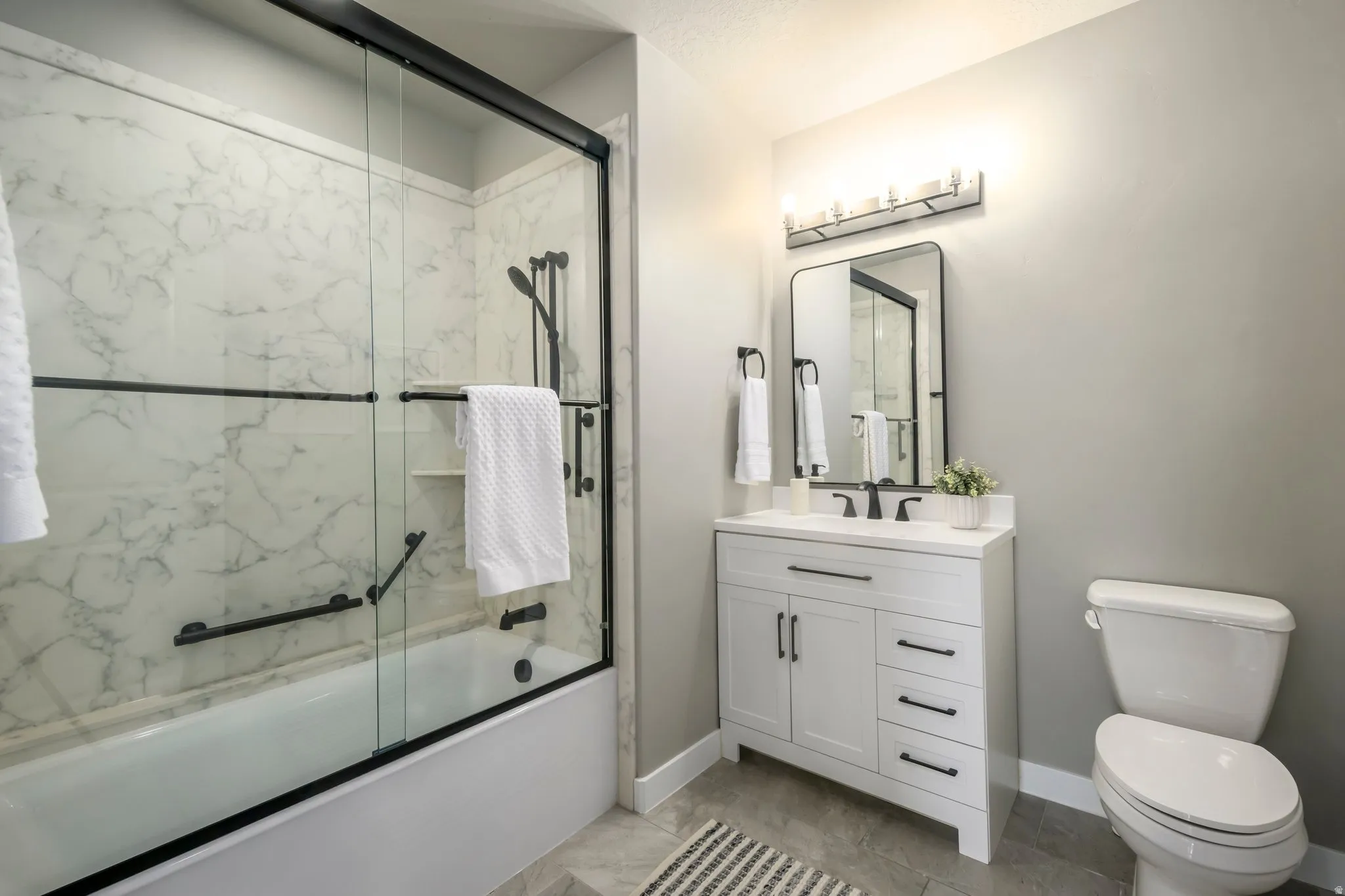 Spa-inspired primary bathroom showcasing a frameless glass-enclosed shower with marble tile surround, white vanity with dual sinks and ample storage drawers, polished chrome fixtures, and soft ambient lighting