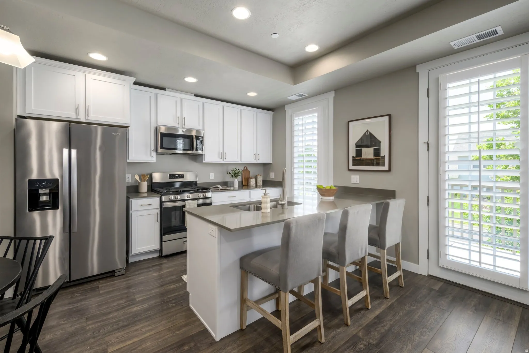 Modern kitchen featuring white cabinetry, stainless steel appliances, a center island with bar seating, and wood-finish flooring