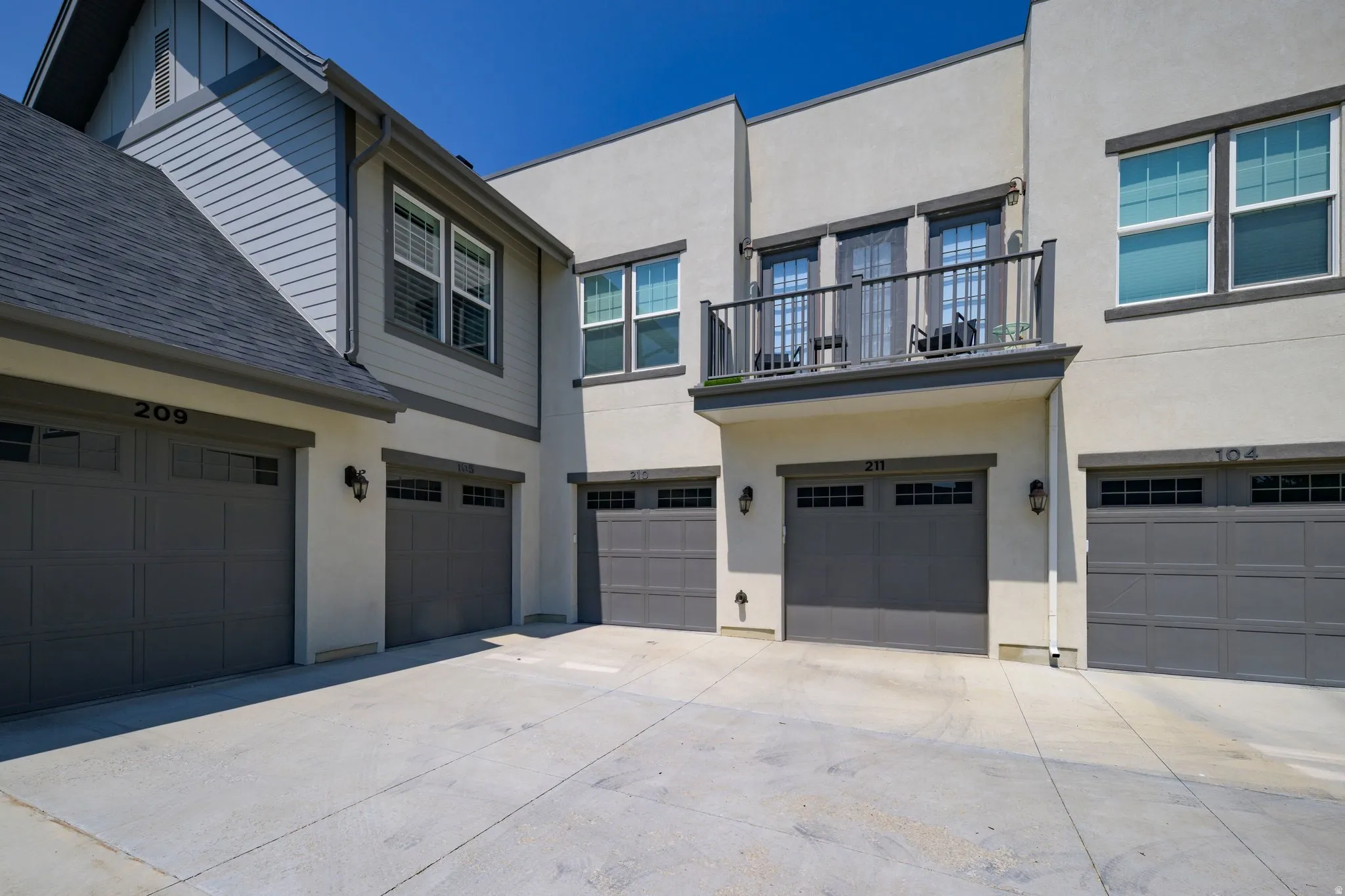 Multi-level townhome exterior featuring individual garages with panel designs and transom windows