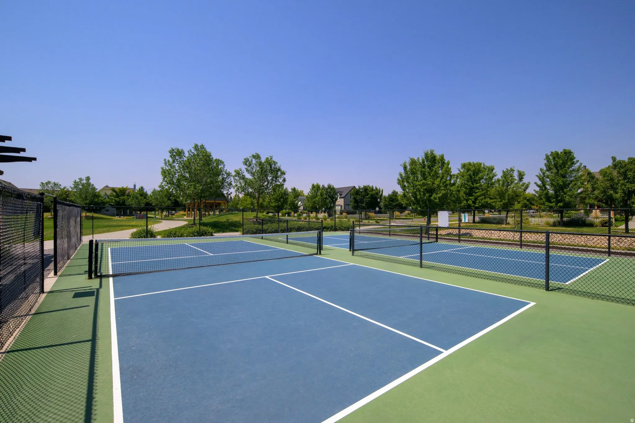 Multiple blue-surfaced courts with white boundary lines and perimeter fencing