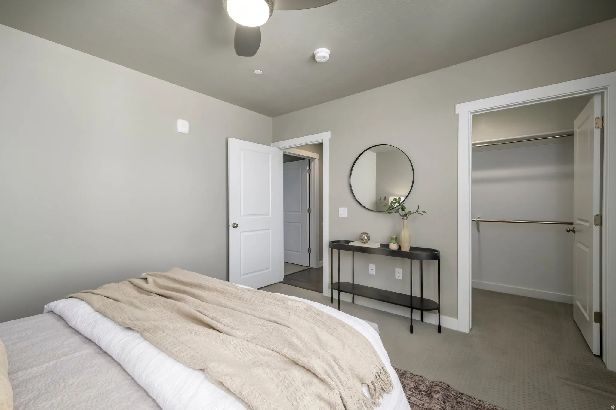Spacious room featuring neutral carpeting, a ceiling fan, a walk-in closet with shelving and hanging rods, and a two-panel interior door