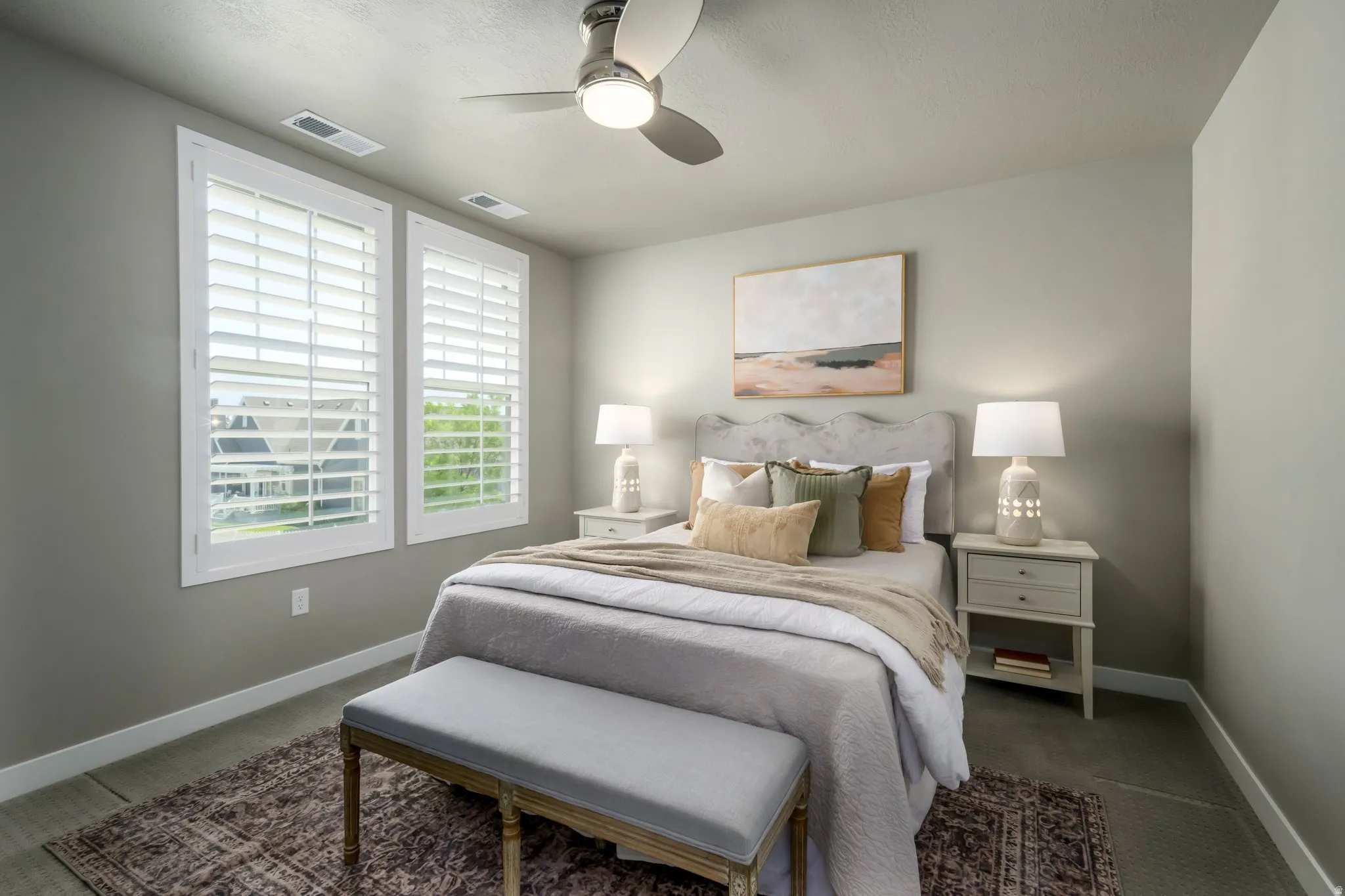Neutral tone walls with white trim, two windows featuring plantation shutters, and a ceiling fan with integrated lighting