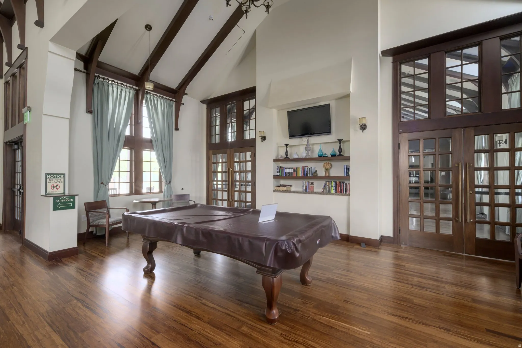 Spacious room featuring wood-finish flooring and a high vaulted ceiling with exposed dark wood beams