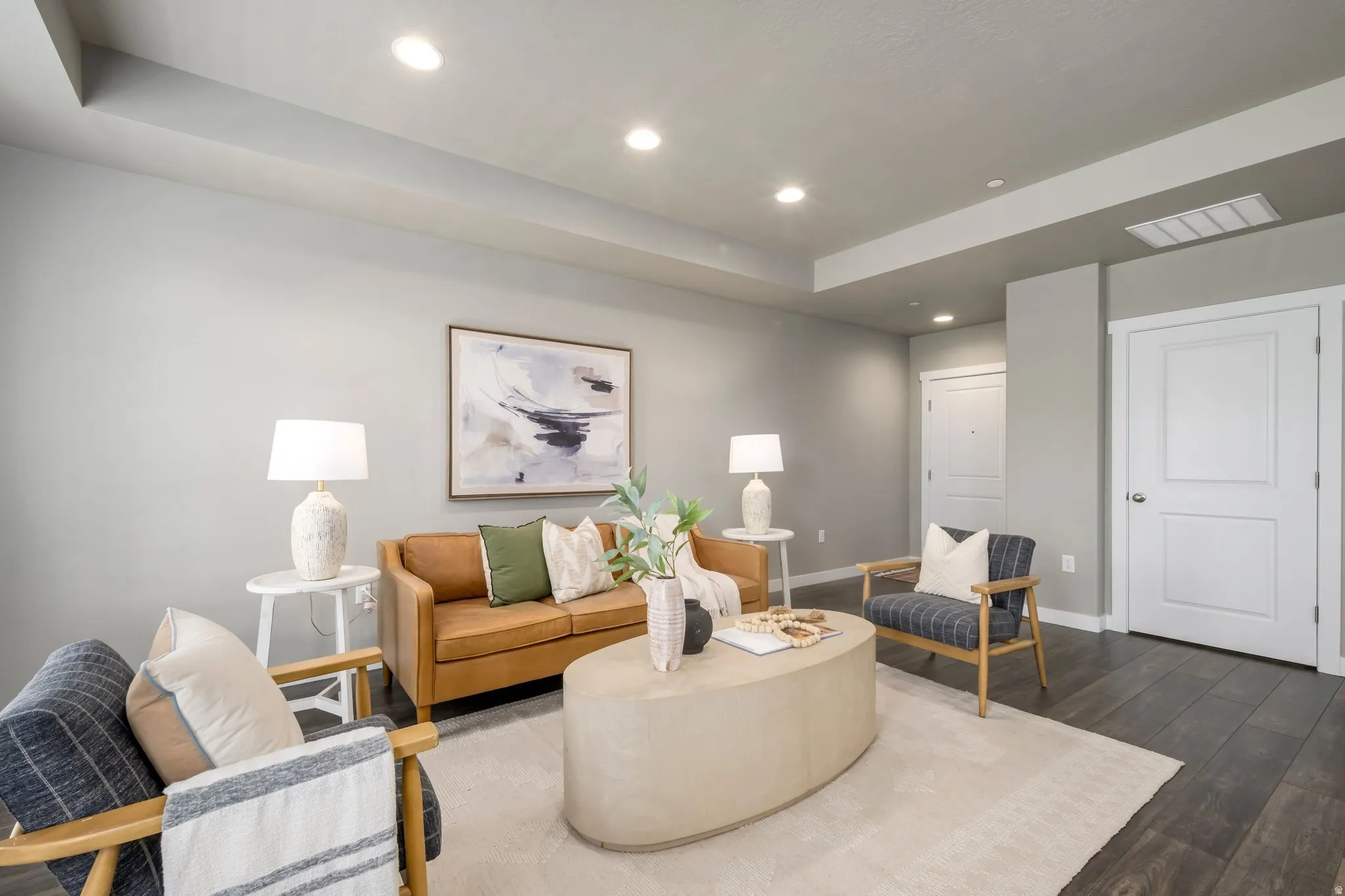 Living area featuring recessed lighting, tray ceiling detail, wood-finish flooring, white doors with paneling, and neutral wall tones