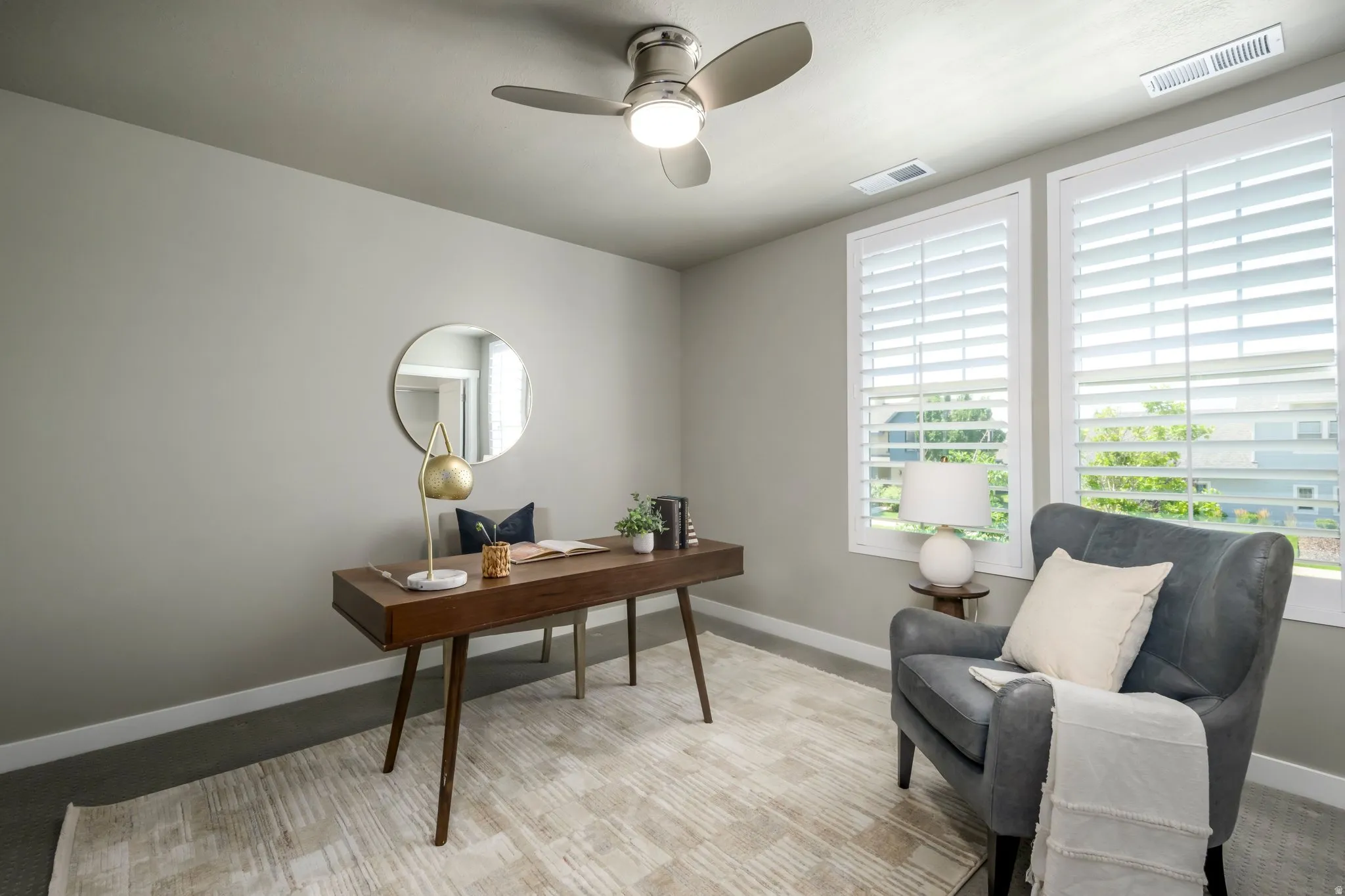 Room featuring two large windows with white plantation shutters, a ceiling fan with integrated lighting, recessed ventilation, and neutral wall paint