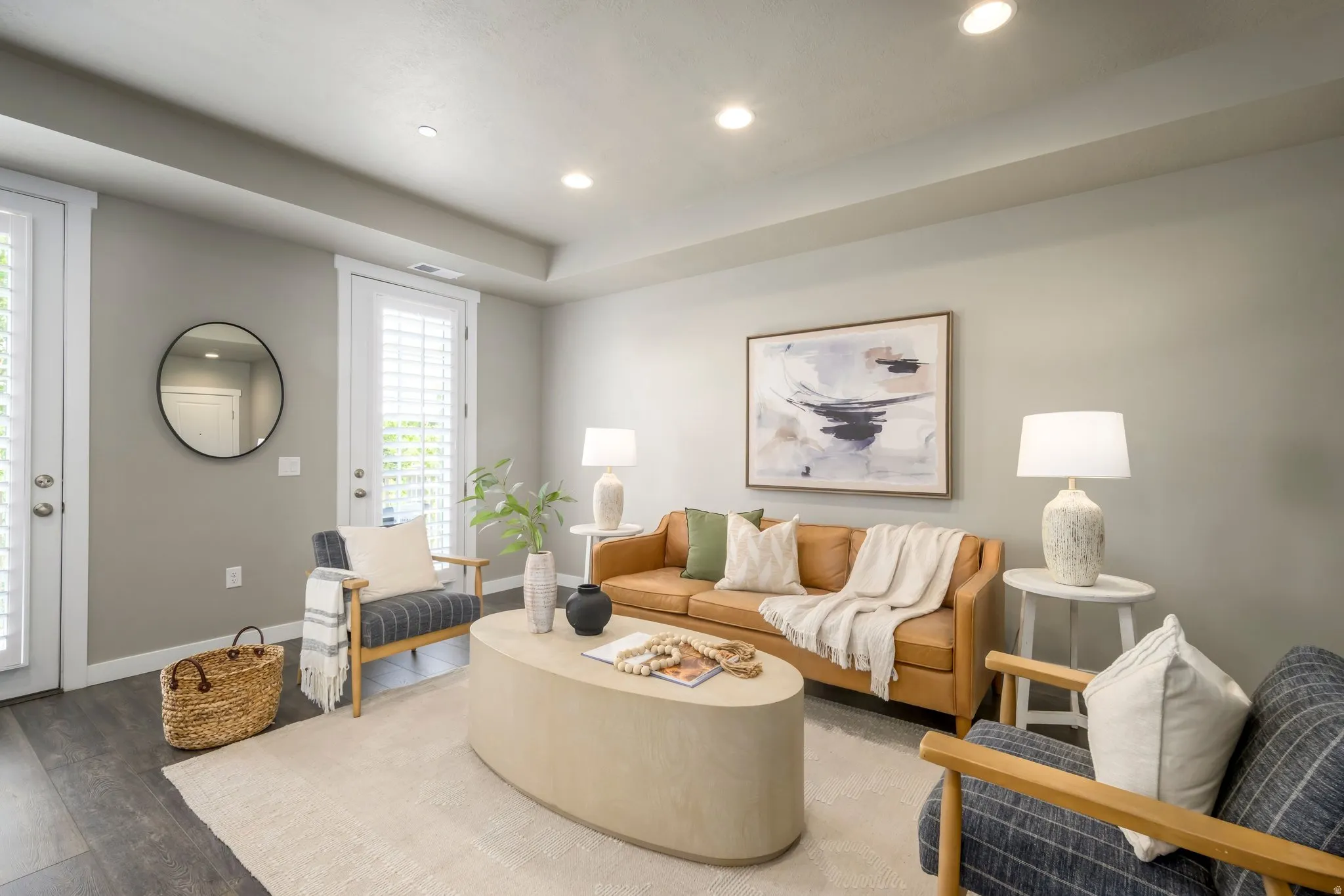 Spacious living area featuring wood-finish flooring, recessed lighting, and white plantation shutters on exterior doors
