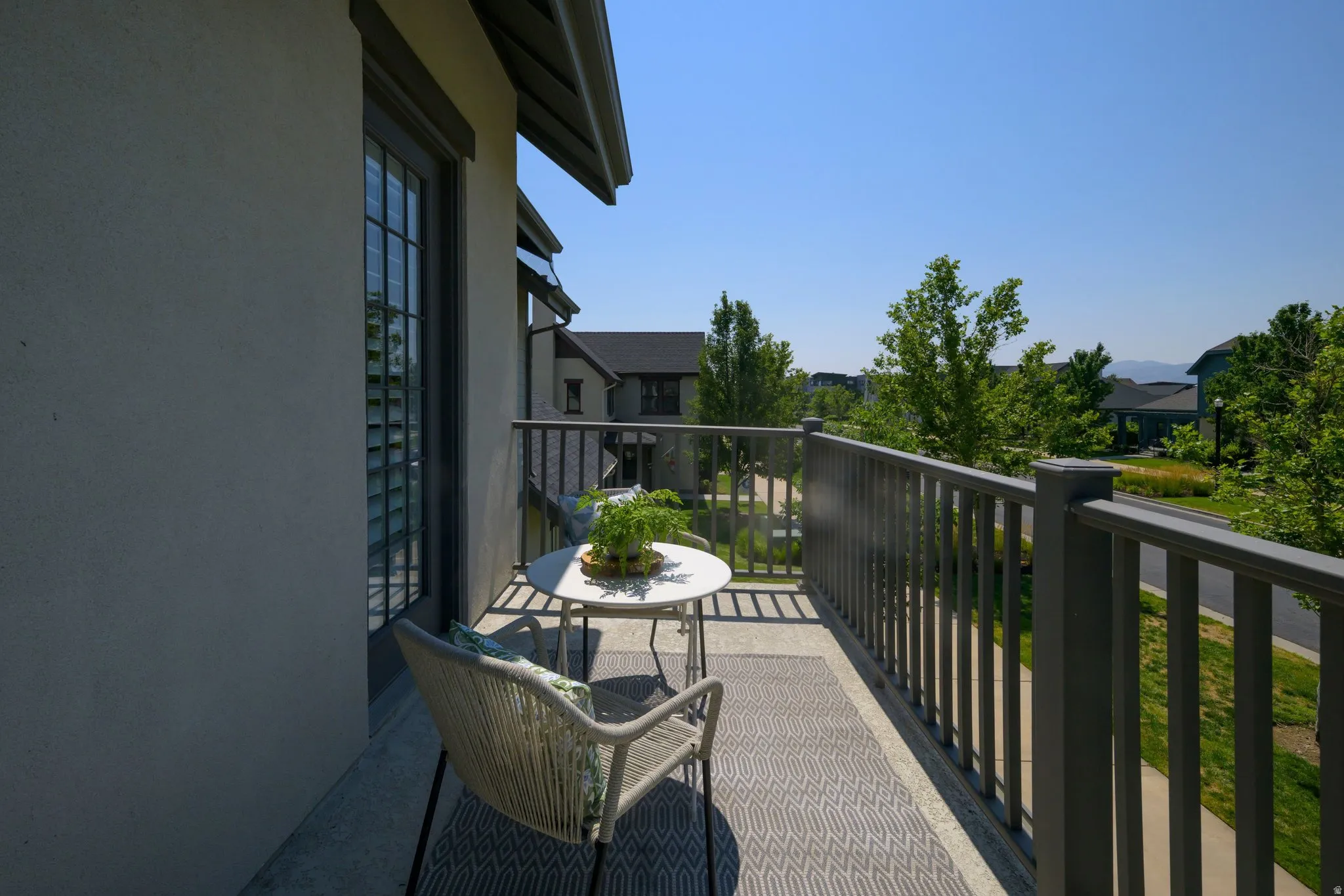 Private balcony featuring a stucco exterior, dark-framed window with louvered shutters, and composite decking