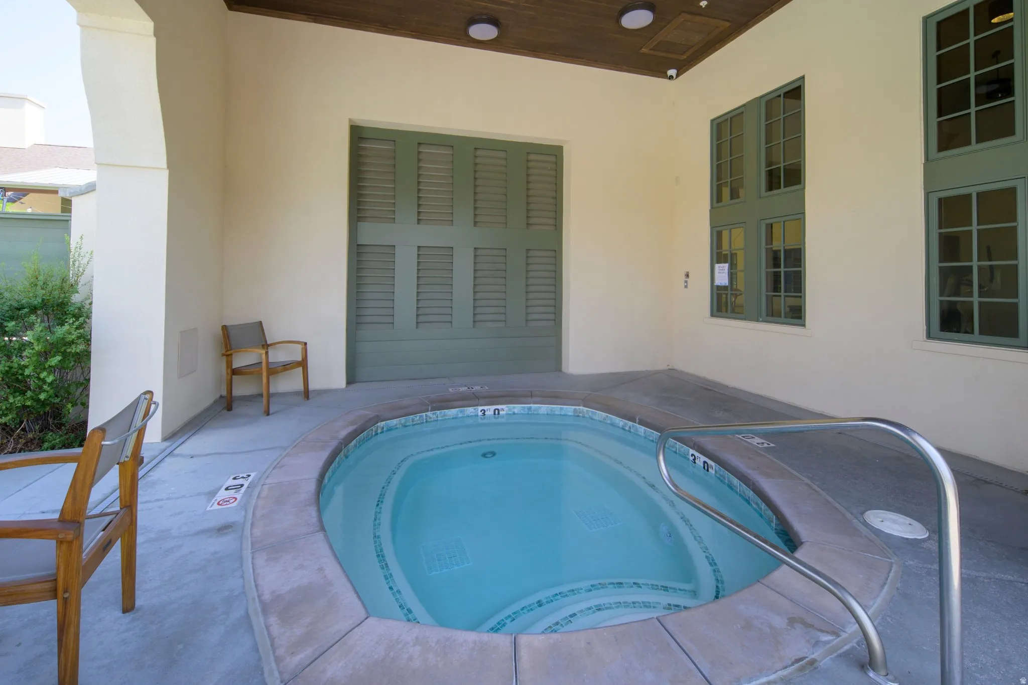 Built-in spa with stone coping and stainless steel handrail set on a concrete patio