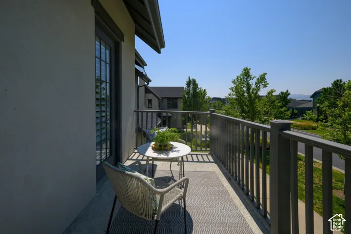 Private balcony featuring a stucco exterior, dark-framed window with louvered shutters, and composite decking