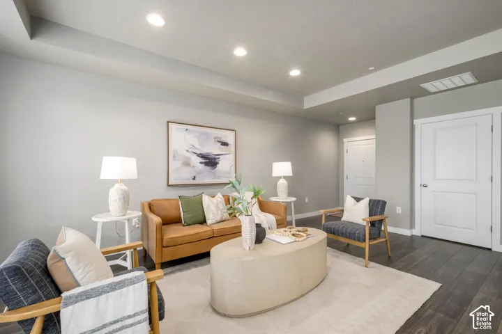 Living area featuring recessed lighting, tray ceiling detail, wood-finish flooring, white doors with paneling, and neutral wall tones