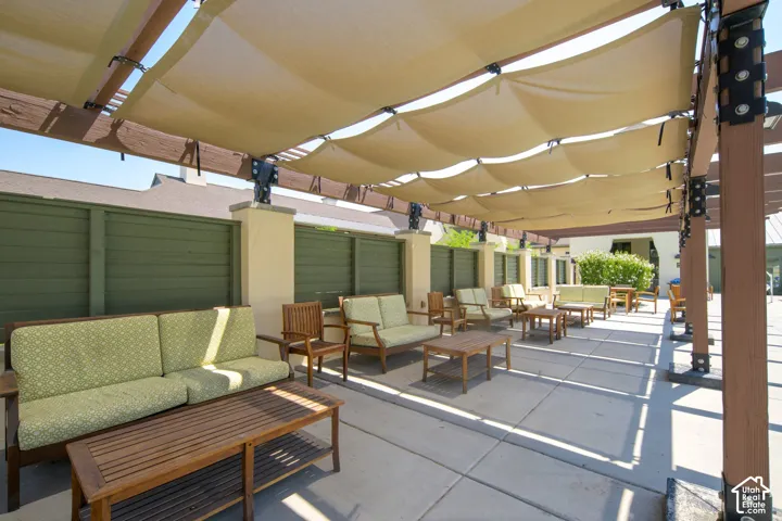 Expansive outdoor patio featuring a large shade structure with adjustable fabric canopies, concrete flooring, and decorative privacy fencing