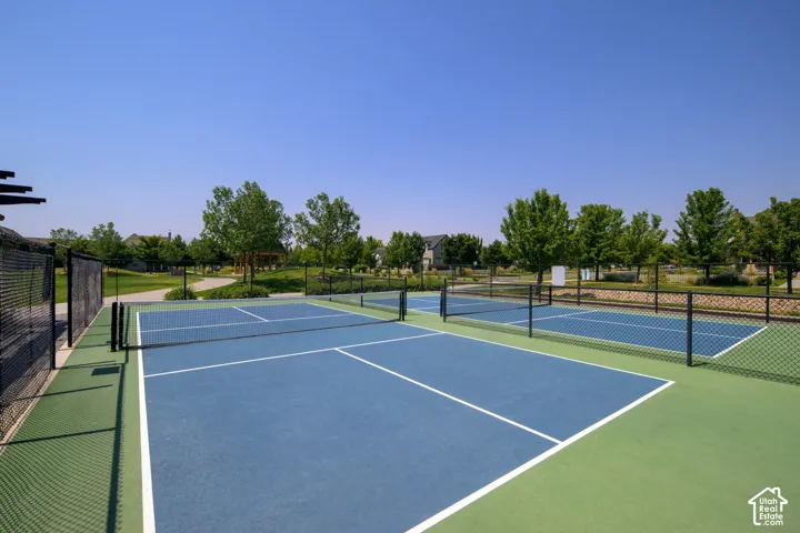 Multiple blue-surfaced courts with white boundary lines and perimeter fencing