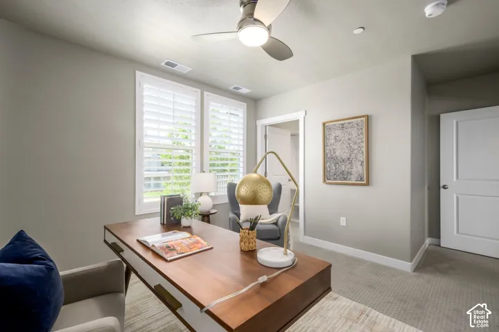 Room featuring two windows with white plantation shutters, neutral-toned walls, and a ceiling fan with integrated lighting