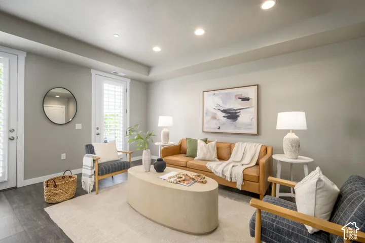 Spacious living area featuring wood-finish flooring, recessed lighting, and white plantation shutters on exterior doors