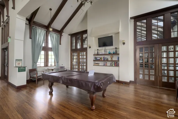 Spacious room featuring wood-finish flooring and a high vaulted ceiling with exposed dark wood beams