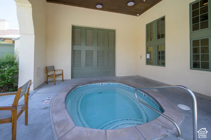 Built-in spa with stone coping and stainless steel handrail set on a concrete patio