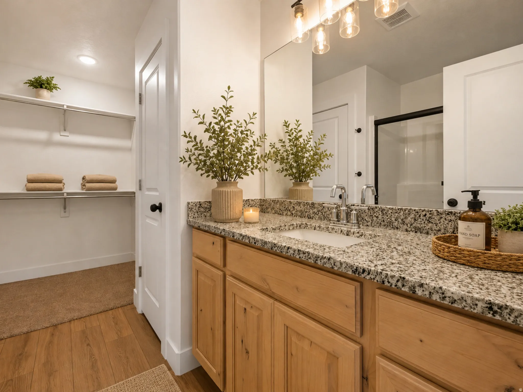 Bathroom vanity featuring a light wood-finish cabinet with multiple drawers and doors, a speckled countertop with an integrated sink, and a chrome faucet