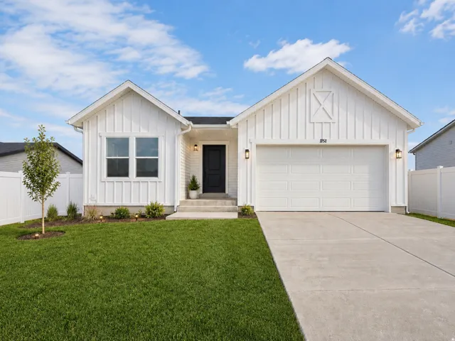 Contemporary farmhouse-style residence featuring white board and batten siding, a prominent attached garage, and a dark front entry door