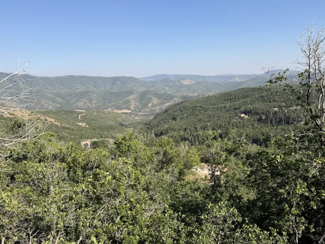 Expansive mountain landscape with diverse foliage under a clear sky
