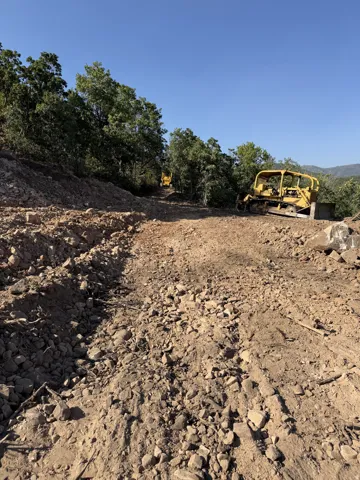 Cleared land parcel featuring natural terrain and mature trees