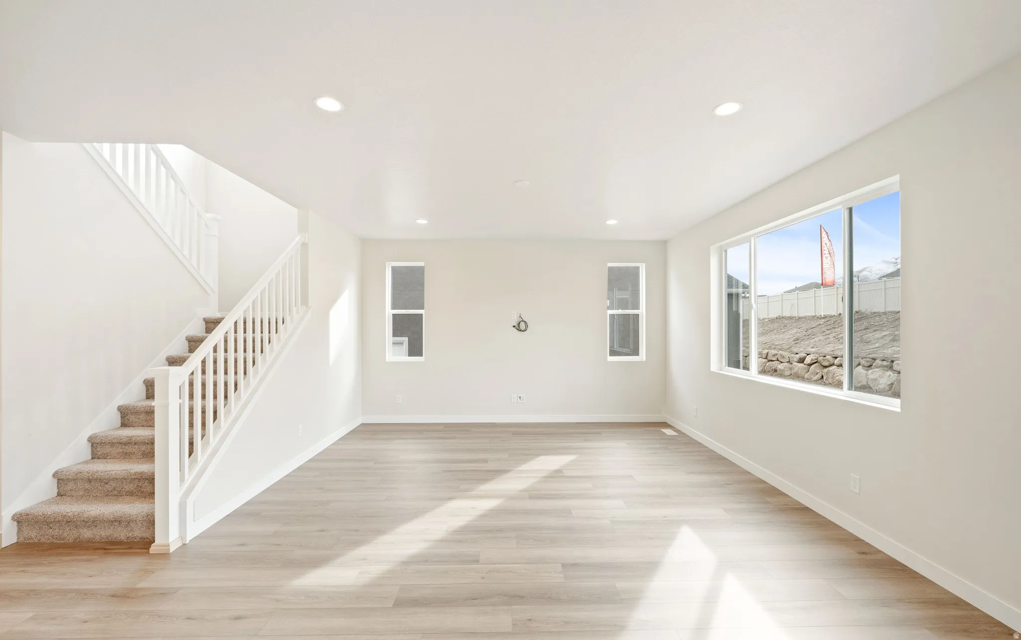 Spacious room featuring light wood-finish flooring and recessed lighting