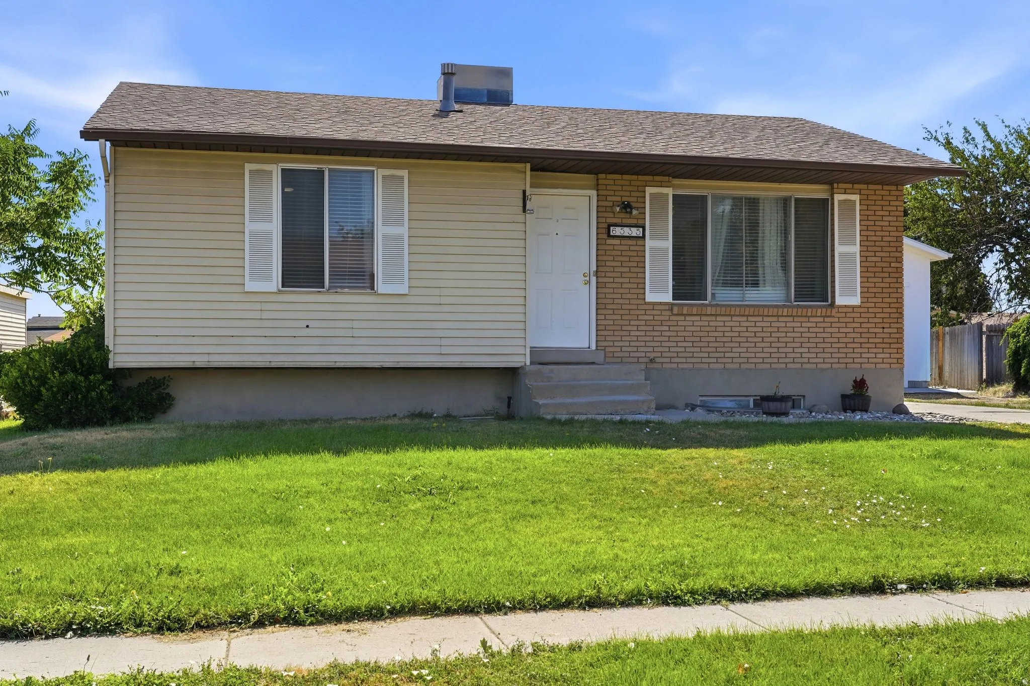 Exterior facade featuring brick and horizontal siding, a gabled roof, and a concrete pathway to the front entry