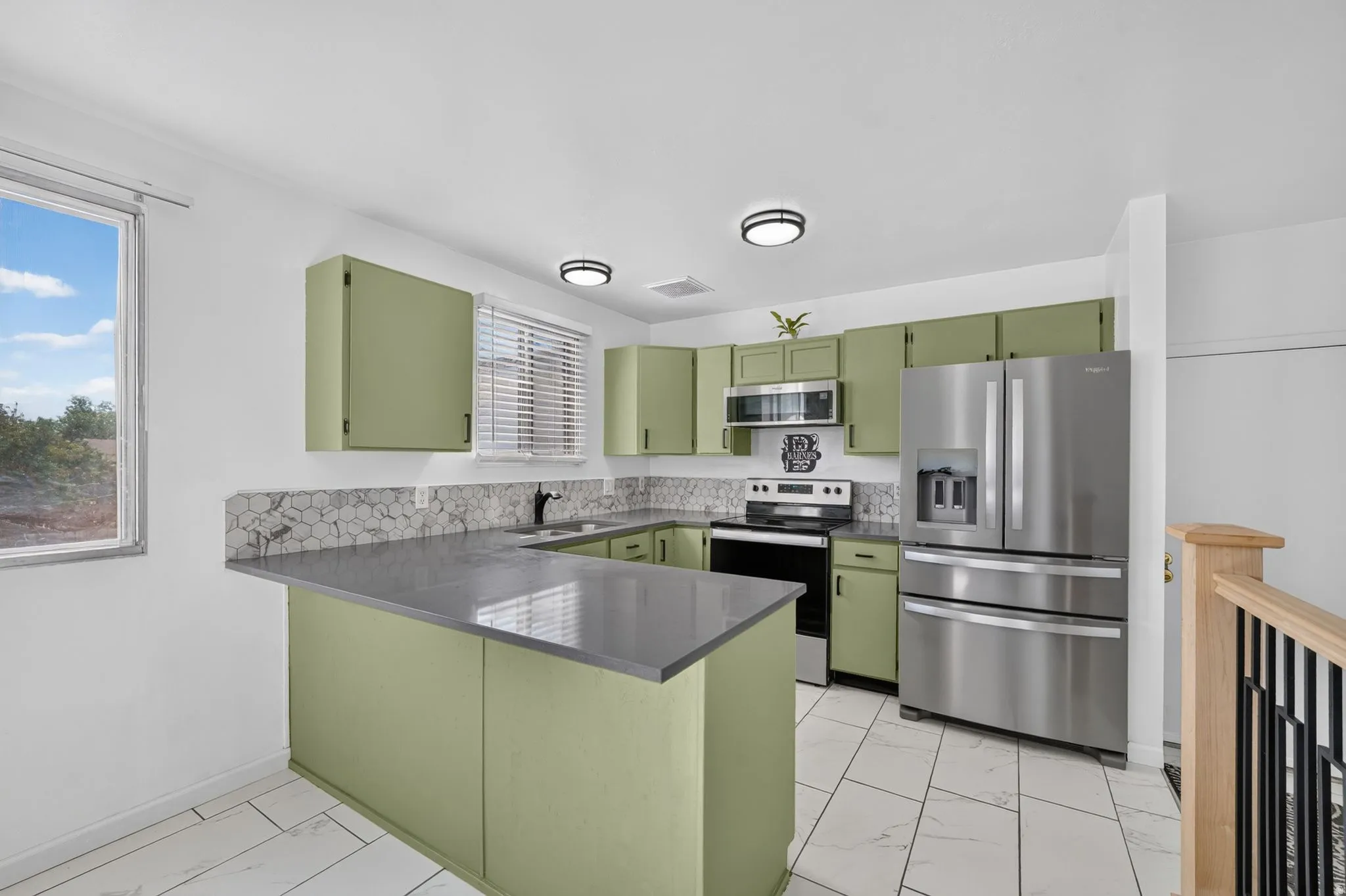 Modern kitchen featuring green cabinetry, stainless steel appliances, and a tiled backsplash