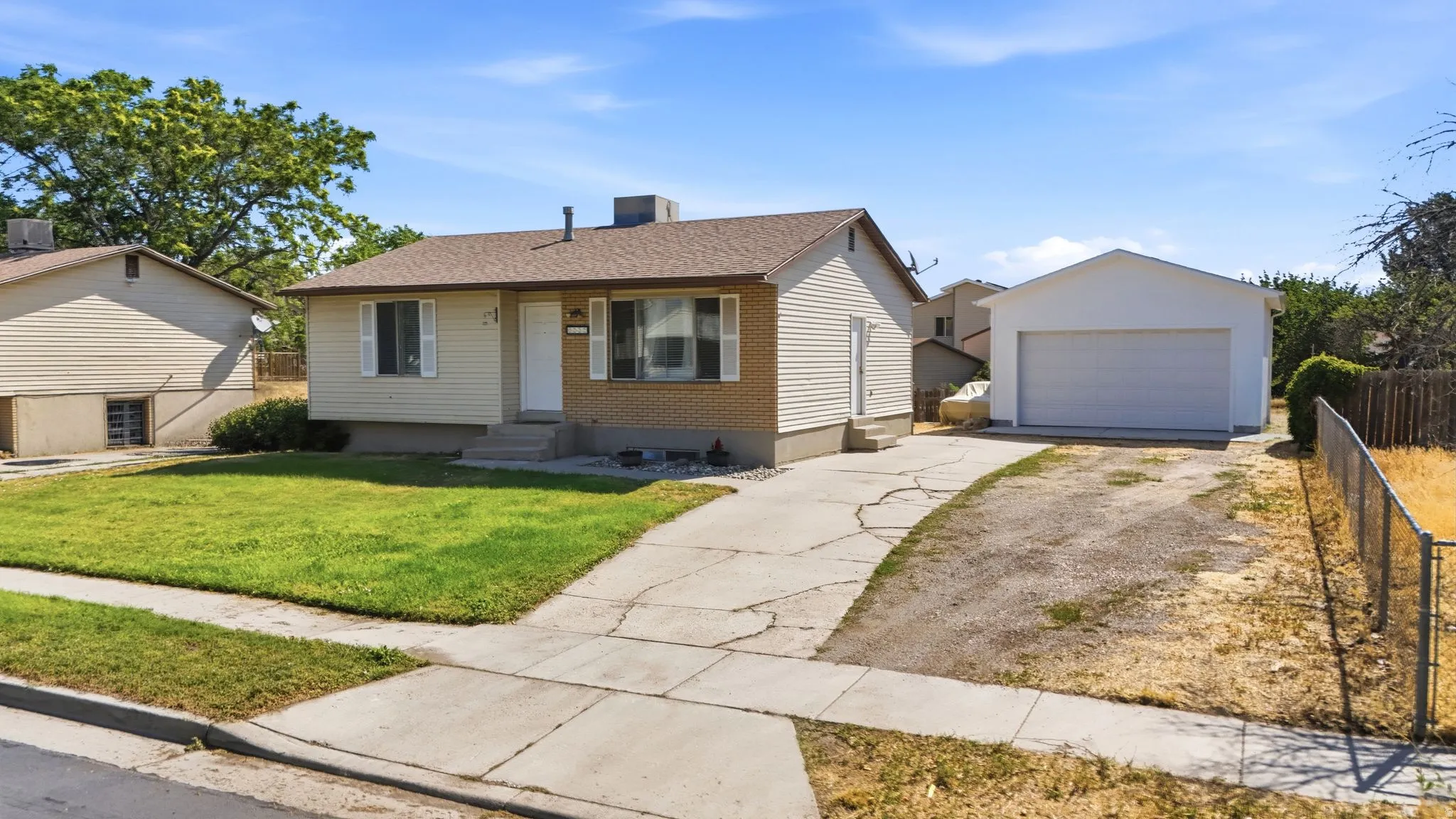 Single-story residence featuring a detached two-car garage, concrete driveway, and front lawn