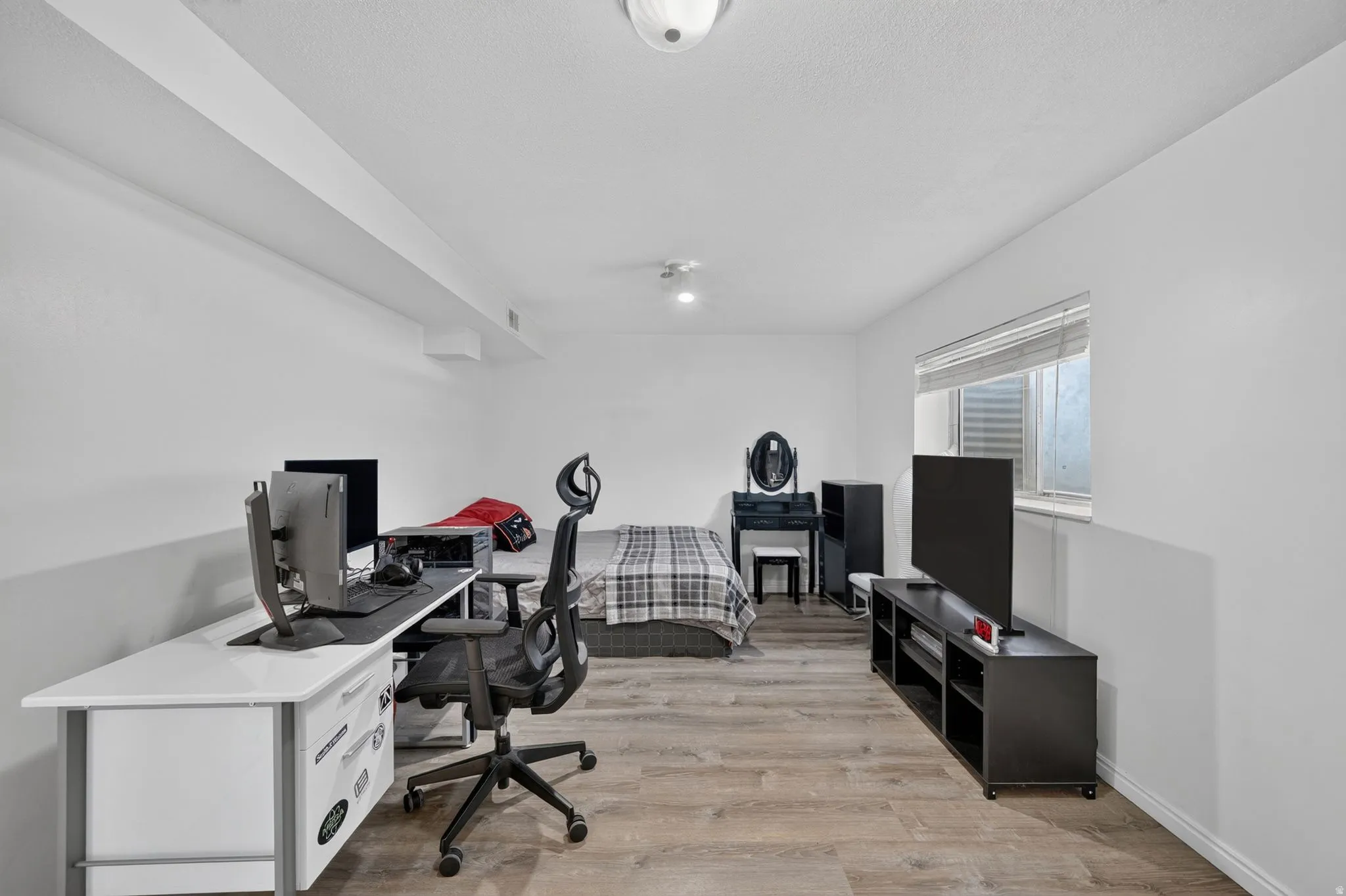 Versatile room featuring wood-finish flooring, white walls, and a window with blinds