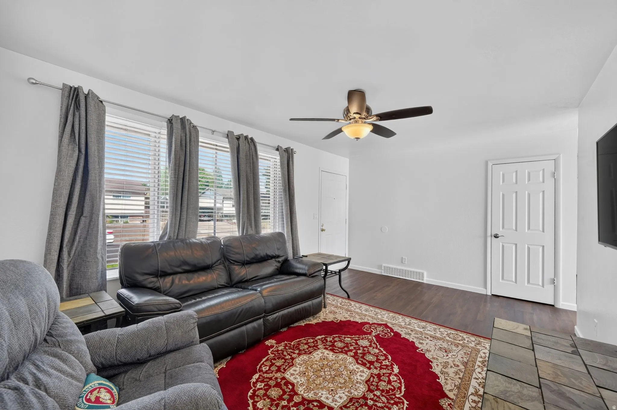 Bright living area featuring wood-finish flooring and a ceiling fan with integrated lighting