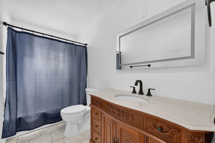 Bathroom featuring an ornate wood vanity with a light-toned countertop, a built-in basin, and a matte black faucet