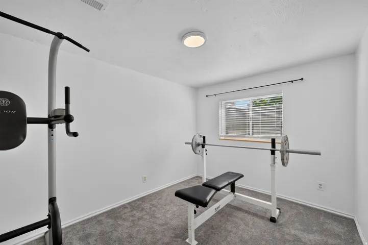 Carpeted room featuring a single window with horizontal blinds, a ceiling-mounted flush light fixture, and white painted walls
