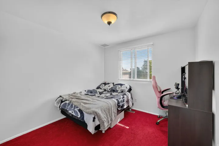 Bedroom featuring bright red carpeting, white walls, and a single window with horizontal blinds