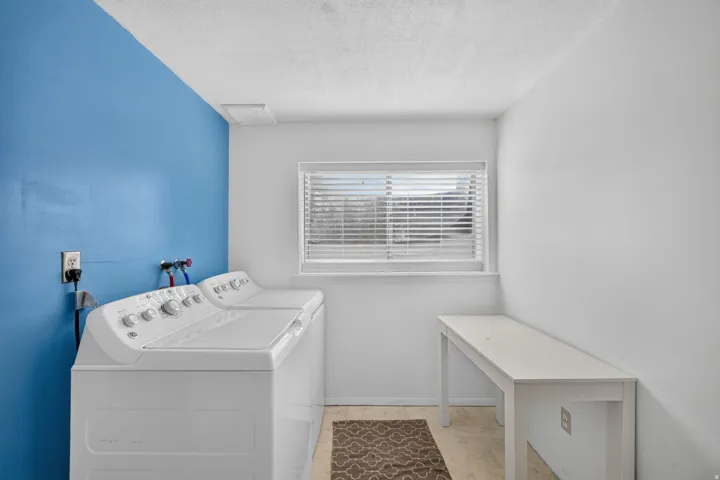Laundry area featuring white walls, a single accent wall in blue, and a window with blinds