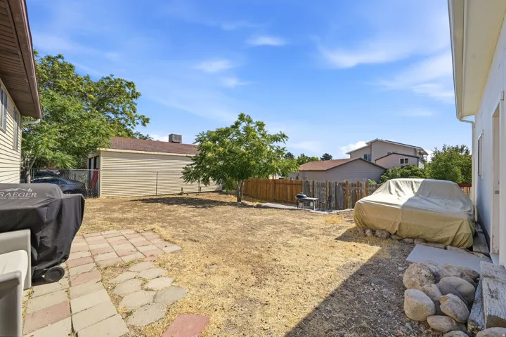 Spacious backyard featuring a detached garage, mature trees, and a combination of wood and chain-link fencing