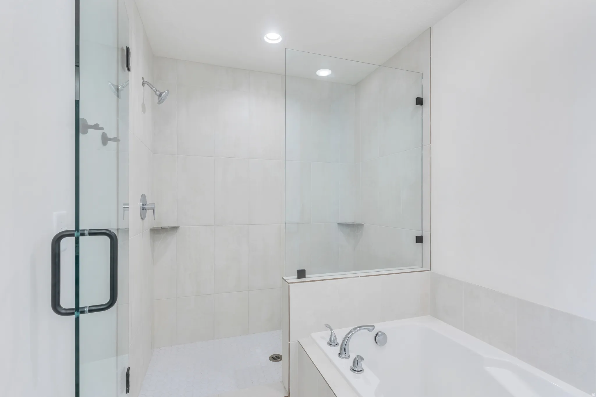 Walk-in shower with clear glass enclosure and black hardware, featuring a rainfall showerhead and integrated shelving