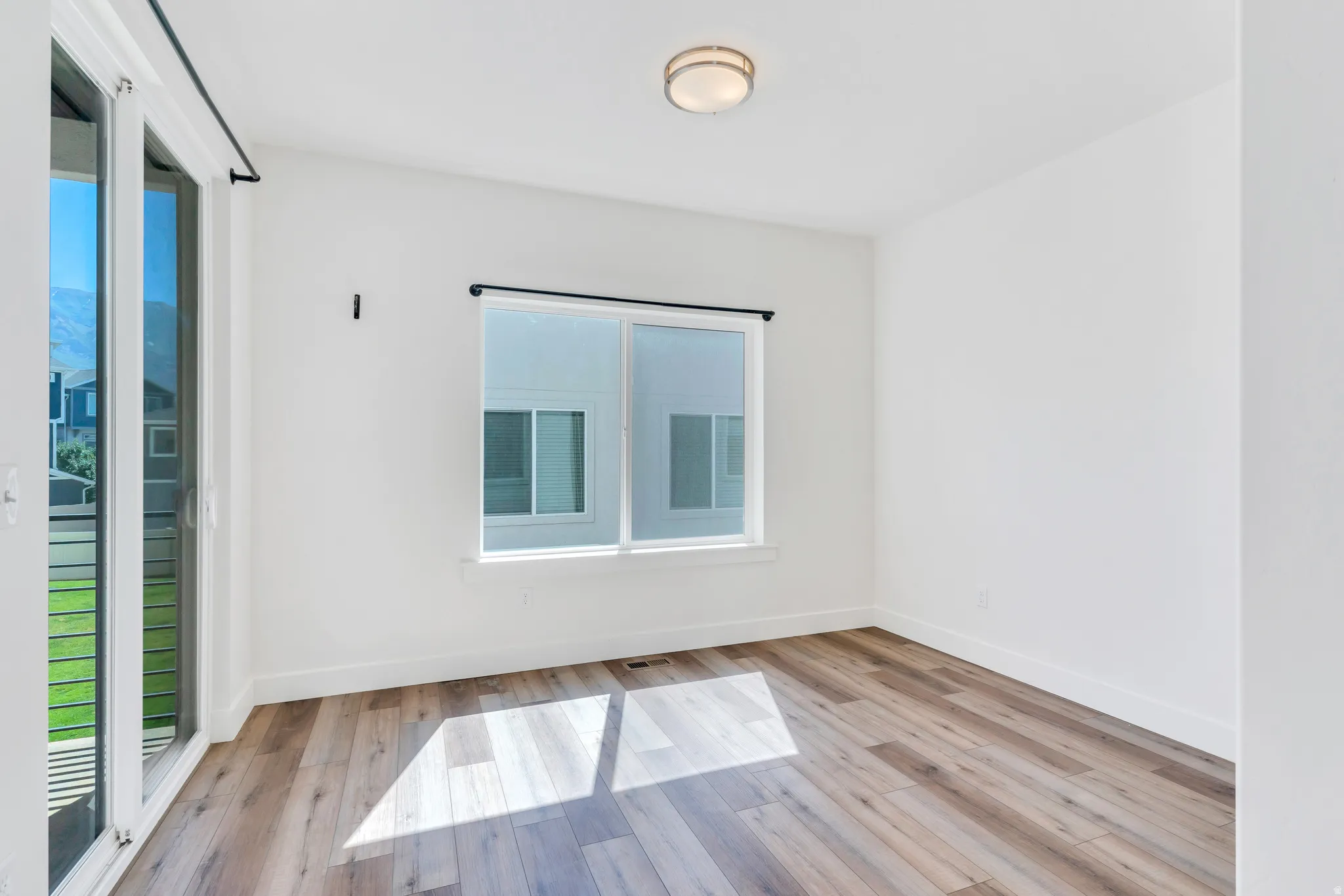 Room featuring wood-finish flooring, white walls, and a contemporary flush-mount ceiling light