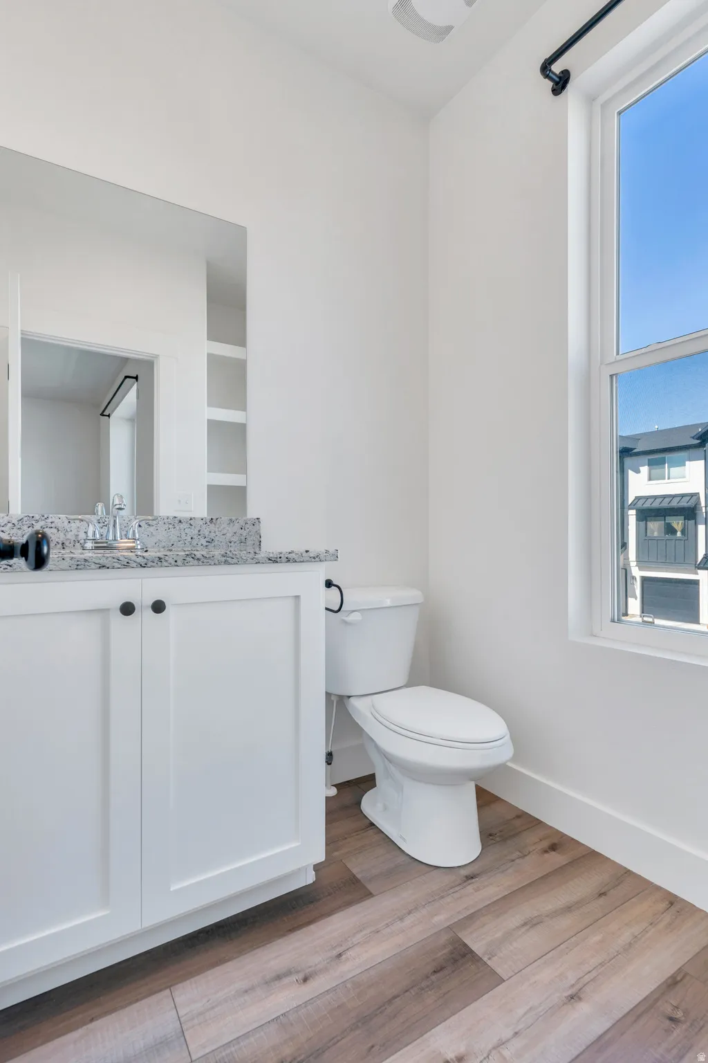 Bathroom featuring a white vanity with a speckled countertop, undermount sink, and black hardware