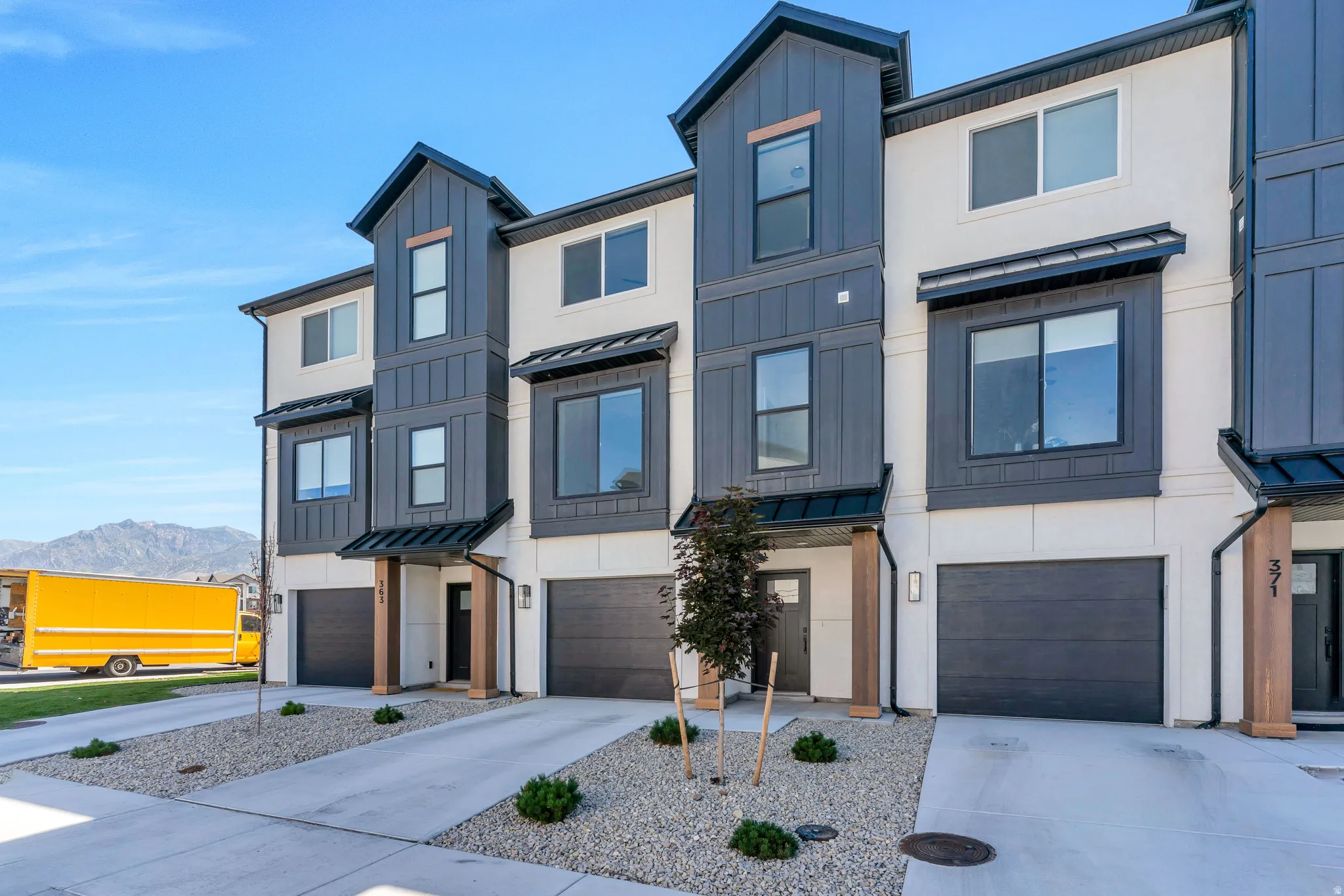 Modern townhome exterior featuring a two-tone facade with white stucco and dark vertical siding